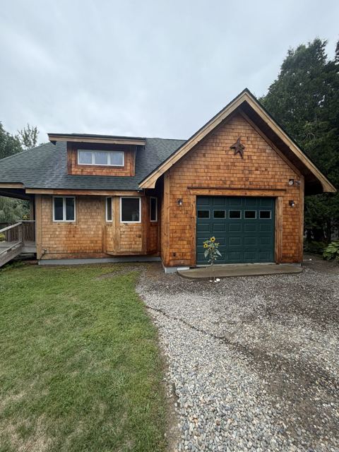 Cedar shingle house with a freshly painted green garage door
