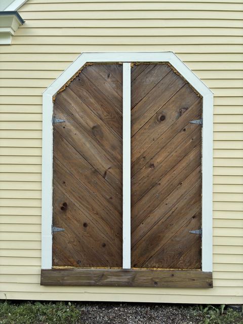 Chevron-pattern wooden doors set in new white trim on yellow siding