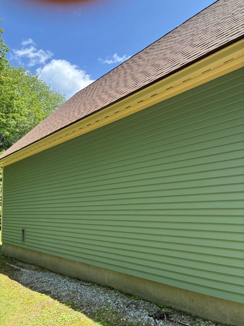 Freshly painted green clapboard siding with yellow soffit trim