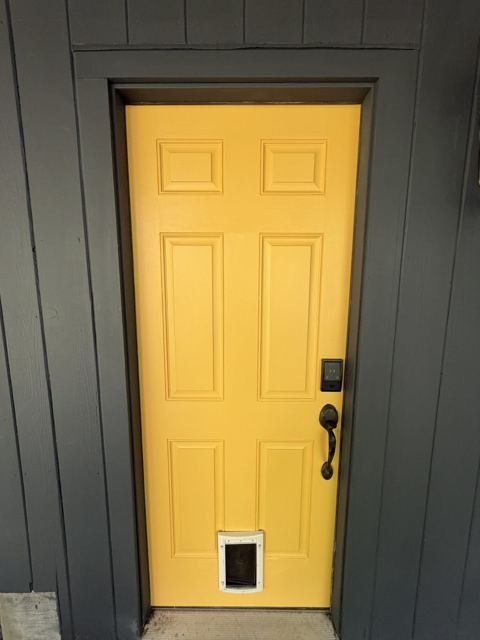 Yellow painted door against charcoal siding